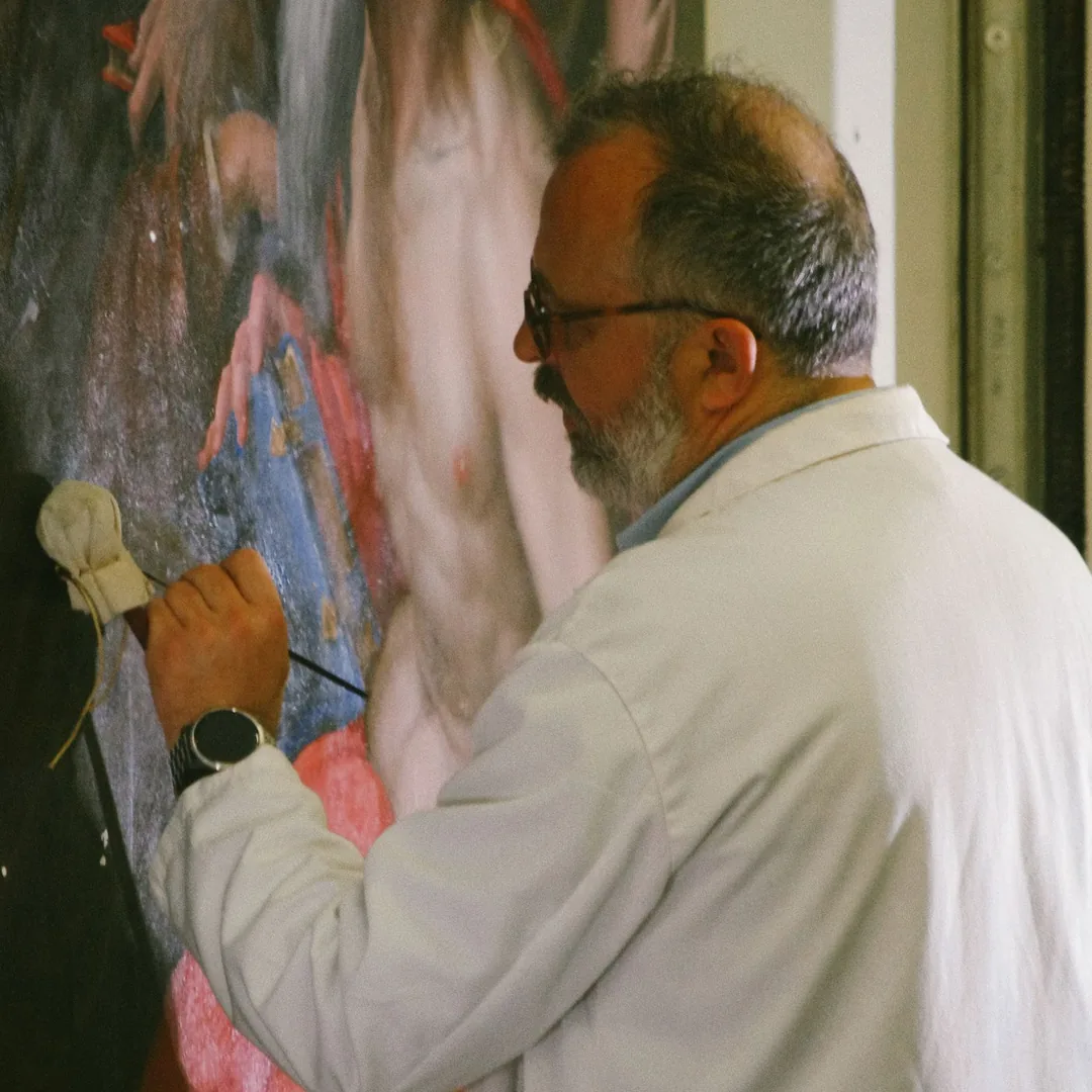 Restaurador aplicando un hisopo de algodón sobre la superficie de una pintura durante una limpieza